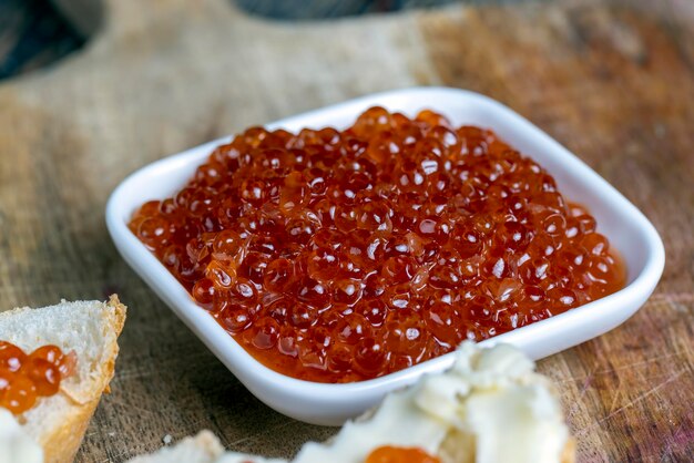 Caviar de saumon ou de truite rouge avec baguette blanche et beurre faisant des sandwichs avec du beurre de pain et du vrai caviar rouge