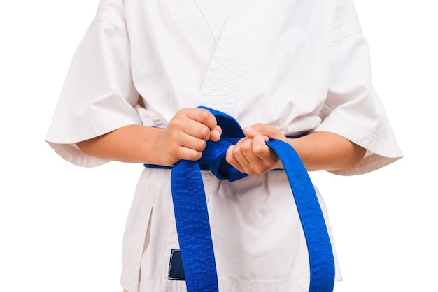 Photo ceinture bleue. petit garçon en kimono attachant le noeud à sa ceinture noire