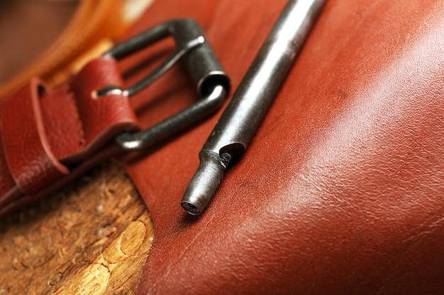 Photo ceinture en cuir et poinçons sur la table en gros plan