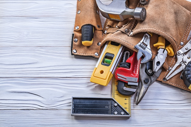 Ceinture à outils en cuir marron avec des outils de construction sur planche de bois