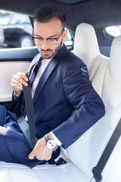 Ceinture En Voiture. Jeune Homme D'affaires Barbu Portant Des Lunettes Attachant La Ceinture De Sécurité Dans La Voiture