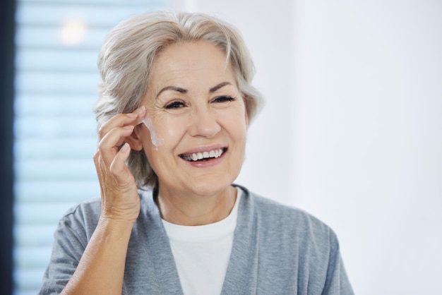 Cela me donne l'air jeune Photo d'une femme âgée passant par sa routine de soins de la peau à la maison