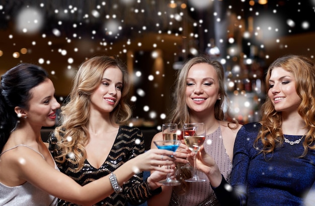 Photo célébration, amis, nouvel an, noël et concept de vacances d'hiver - femmes heureuses buvant du champagne et des cocktails lors d'une soirée entre célibataires dans une boîte de nuit sur la neige