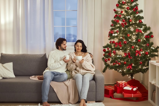 Célébration de couple nouvel an près de l'arbre de noël à la maison