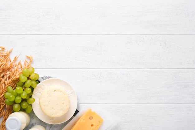 Célébration de la fête juive de Chavouot Lait et fromage blé mûr et crème de fruits Produits laitiers sur fond de bois blanc Concept de Chavouot Vue de dessus Maquette