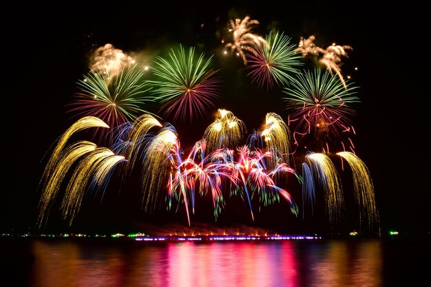 Célébration de feux d'artifice colorés et fond du ciel nocturne avec réflexion sur l'eau