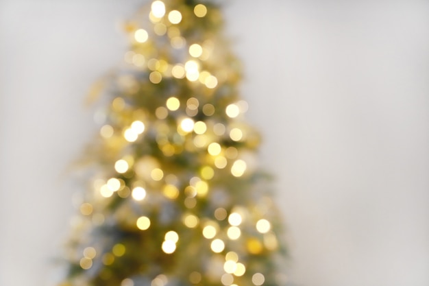 Célébration de la lumière floue sur l'arbre de Noël avec fond de mur blanc. Fond de vacances de défocalisation.