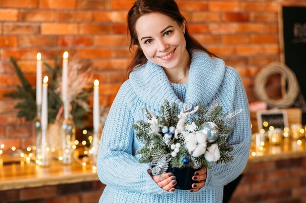 Célébration de Noël. Portrait de femme joyeuse tenant le cadeau d'arrangement de sapin.