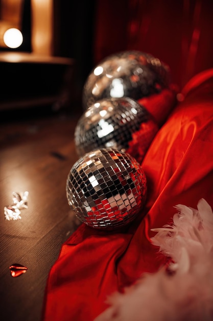 Célébration de la saint-valentin à l'intérieur de la chambre riche avec des boules disco près du lit par des draps en soie rouge