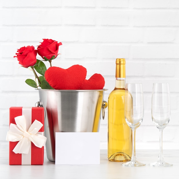 Célébration de la Saint-Valentin avec vin, cadeau et bouquet de roses pour les voeux de vacances.
