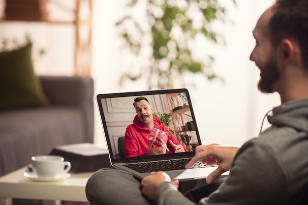 Célébration et vacances pendant le concept de quarantaine. Des amis ou de la famille déballent des cadeaux tout en parlant par appel vidéo. Ayez l'air heureux, joyeux, sincère. Concept de nouvel an, technologies, émotions.