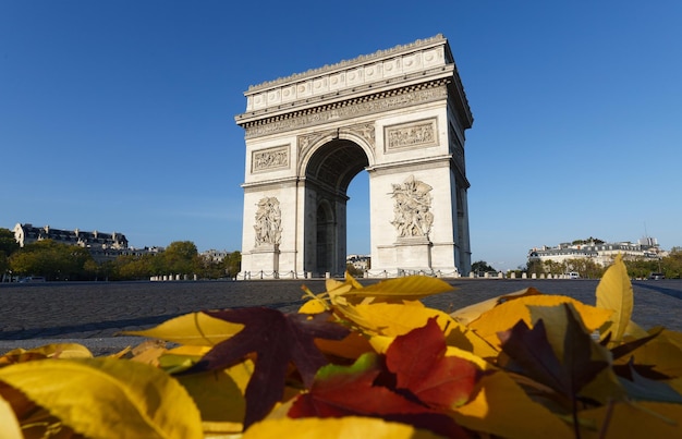 Le célèbre Arc de Triomphe et les feuilles d'automne au premier plan à la journée ensoleillée Paris France
