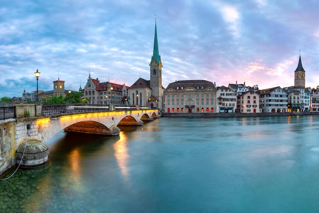 Célèbre église Fraumunster et pont Munsterbrucke sur la rivière Limmat au coucher du soleil dans la vieille ville de Zurich, la plus grande ville de Suisse