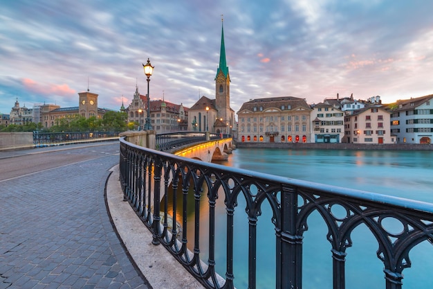 Célèbre église Fraumunster et pont Munsterbrucke sur la rivière Limmat au lever du soleil dans la vieille ville de Zurich, la plus grande ville de Suisse