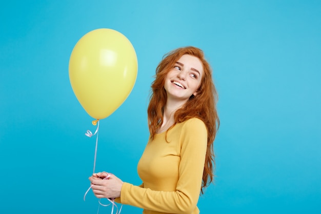 Célébrer le concept - Close up Portrait heureux jeune fille attrayante belle redhair souriante avec un ballon de fête colorée. Blue Pastel Background.