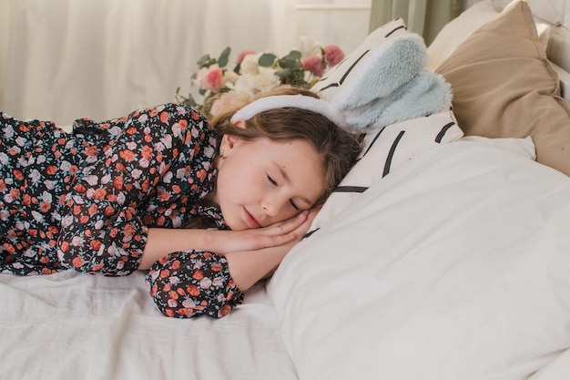 Célébrer la fille de Pâques avec des oreilles de lapin au lit