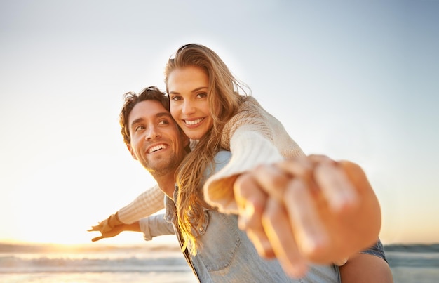 Célébrer leur amour Un jeune couple heureux célébrant ensemble leur amour au bord de la mer