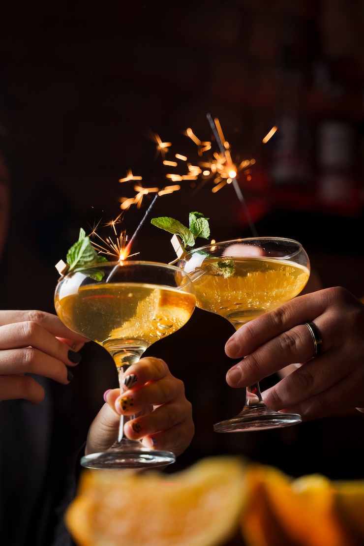 Photo célébrer le nouvel an 2022 avec des feux d'artifice de cierges magiques et boire des cocktails. menthe avec tranche d'orange dans un verre à cocktail rempli de cocktails alcoolisés.