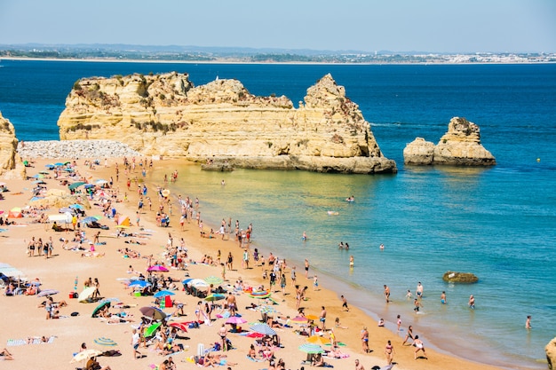 Photo célèbres rochers en mer, océan, lagos au portugal. plage et baigneurs sur la côte de l'algarve