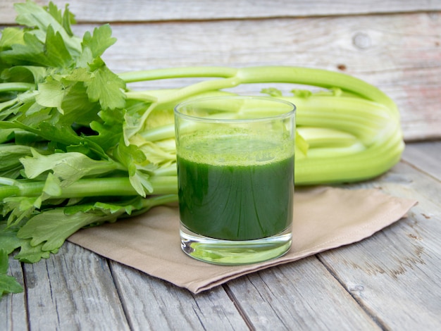 Céleri frais et jus sur une table en bois se bouchent