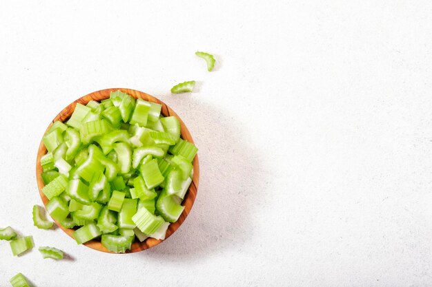 Céleri vert haché dans un bol fond de table blanc vue de dessus espace de copie