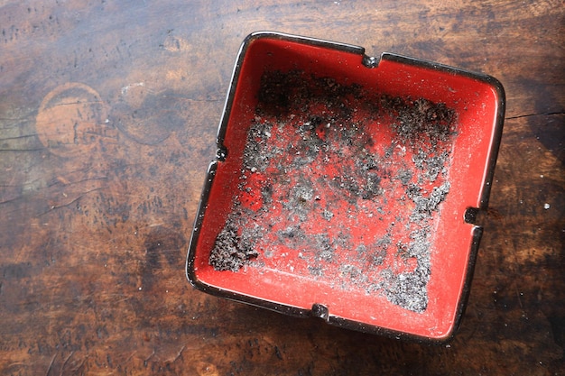 cendrier avec des cendres de cigarettes sur un vieux fond de table en bois à texture sombre grunge