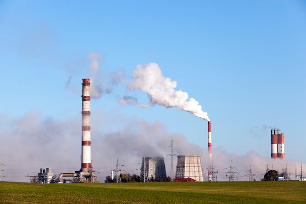 Centrale électrique avec tuyau de fumée pendant le fonctionnement. Photo d'un gros plan à distance. Ciel bleu en saison d'automne