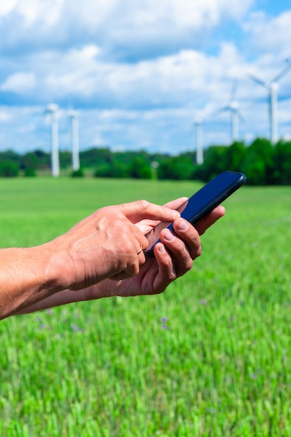 Photo centrale éolienne et main tenant un téléphone intelligent