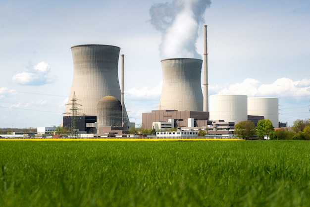 Centrale nucléaire avec champ jaune et gros nuages bleus.