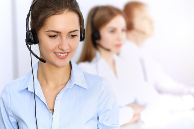 Centre d'appel. Concentrez-vous sur une belle femme d'affaires à l'aide d'un casque dans un bureau ensoleillé.