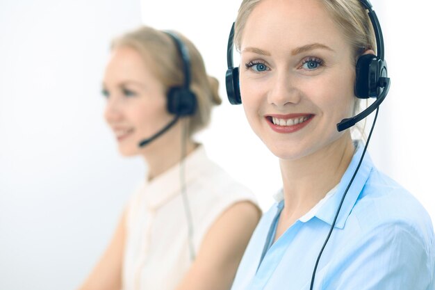 Centre d'appel lumineux et ensoleillé. Groupe de femmes blondes en casque au travail. Concept de bureau et d'entreprise.