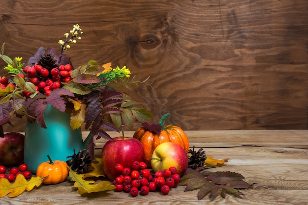 Centre de table d'automne avec baies de rowan, feuilles dans un vase turquoise, espace de copie