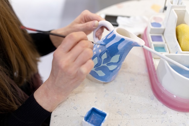 Une céramiste méconnaissable peint un laitier en argile avec un pinceau Concept d'art en céramique