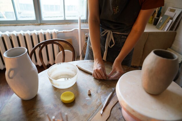 Céramiste en studio façonner les détails de l'argile à partir de la faïence humide pendant la classe de maître d'art en atelier