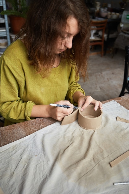 Photo céramiste travaillant dans un atelier de poterie. les mains du céramiste sales d'argile. processus de création de poterie. maître céramiste travaille dans son atelier