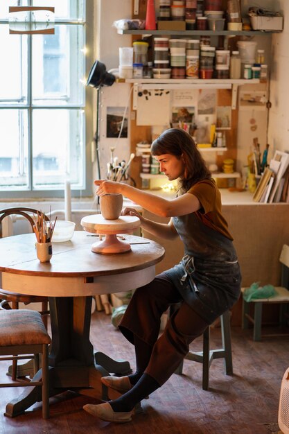 Céramiste en vase de moulage tablier à master class en studio jeune femme propriétaire d'un studio de poterie au travail