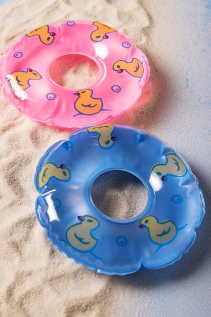 Cercles gonflables roses et bleus sur le sable sur fond bleu imitant l'eau Gros plan