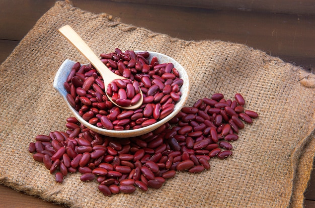 Céréales de haricots rouges dans un bol en bois et une cuillère placés sur un sac