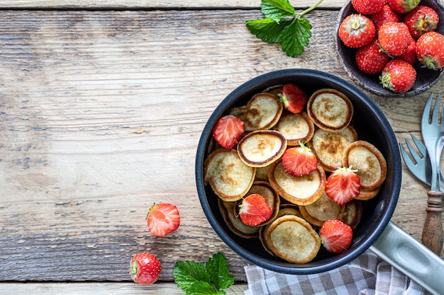 Céréales minuscules aux crêpes aux fraises dans une poêle sur bois