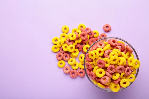 Céréales multicolores aux fruits sur fond violet. Espace vide pour les textes.