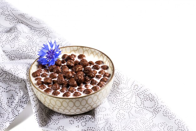 Céréales pour petit déjeuner, céréales au chocolat au lait avec fleur de bleuet sur une serviette blanche, concept d'une alimentation saine pour les enfants avant l'école. Espace copie