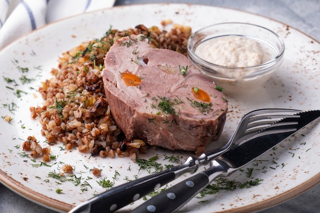 Céréales de sarrasin de porc bouilli servi fourchette et couteau. Fermer