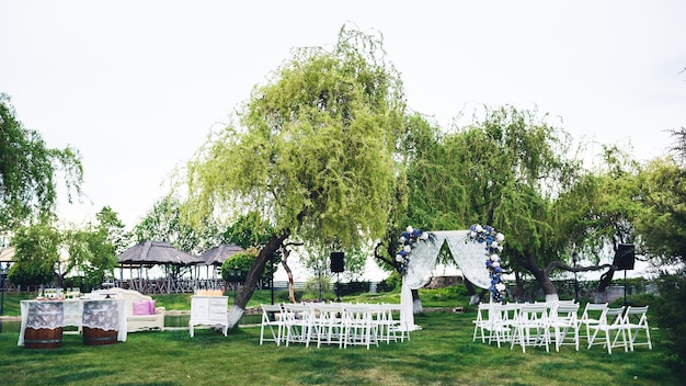 Cérémonie de mariage dans la nature: une arche, des chaises pour les invités, une table de buffet, une photozone.