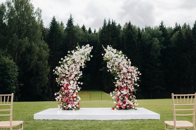 Cérémonie de mariage dans la rue sur la pelouse verte.Décor avec des arches de fleurs fraîches pour la cérémonie.