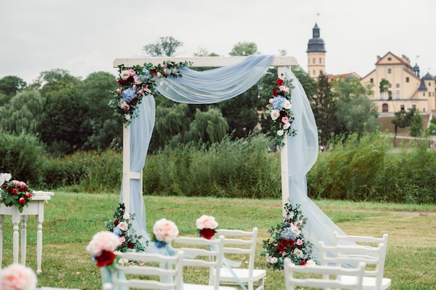 Cérémonie de mariage dans la rue sur la pelouse verte.Décor avec des arches de fleurs fraîches pour la cérémonie.