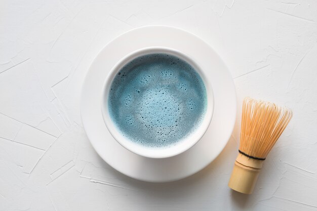 Cérémonie thé bleu matcha et bambou fouet sur table en béton blanc vue de dessus