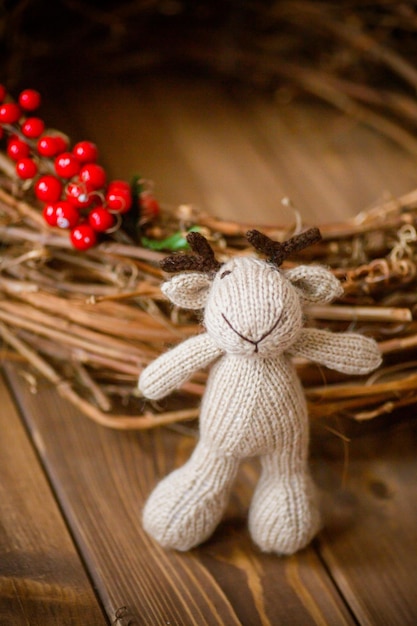 Photo cerf jouet tricoté à la main dans un panier en osier sur un fond en bois