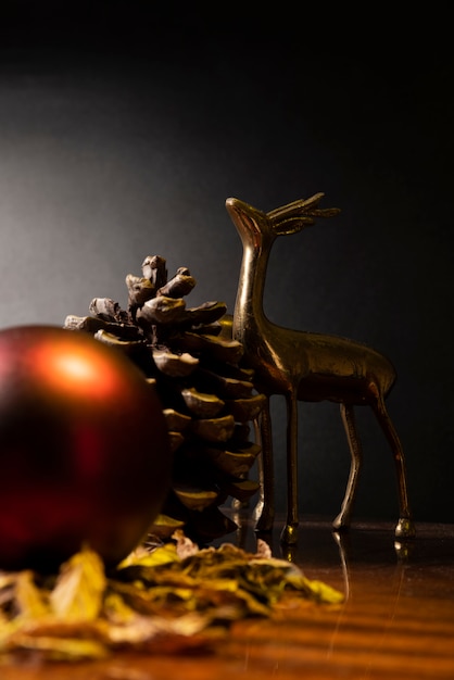 Cerf en métal avec boule de Noël rouge, ananas en pin sec et fond noir