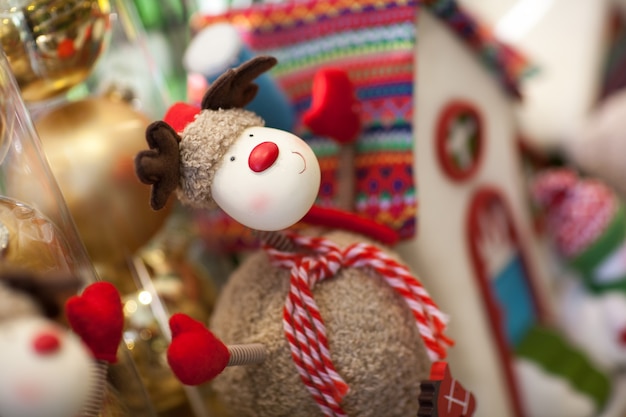 Cerf de Noël en peluche avec une écharpe sur le fond de la maison