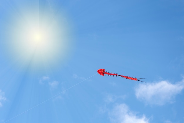 Cerf-volant un cerf-volant multicolore vole dans le ciel bleu ciel avec des nuages et de l'espace soleil pour le texte ou ...